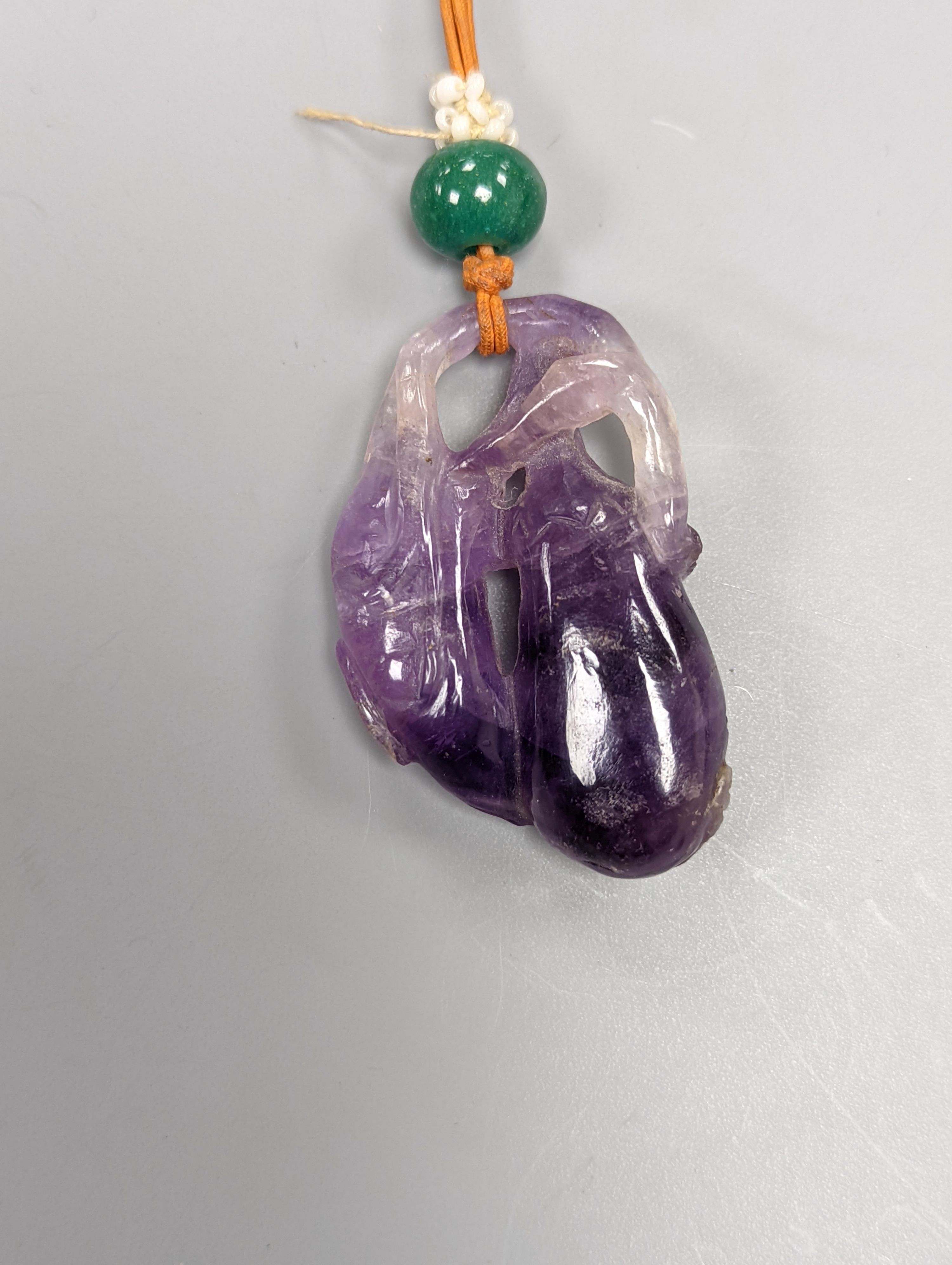 A 19th century Chinese carved amethyst pendant, 5cm on an ornate cord